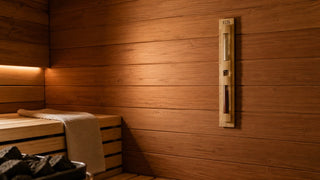 Minimalist sauna interior with traditional wall-mounted sand timer and warm wooden benches