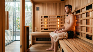 Man sitting inside a modern infrared sauna with glowing infrared heater panels